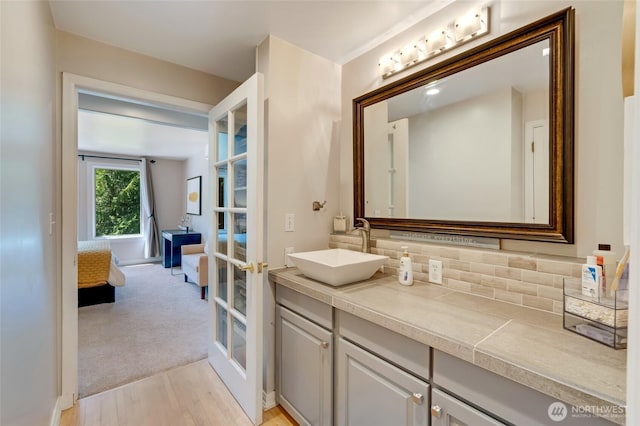 19716 61st Ave SE, Snohomish, WA 98296 - bathroom with french doors, vanity, wood finished floors, backsplash, and ensuite bath