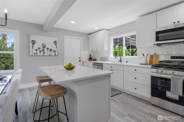 4224 Division Ave W, Bremerton, WA 98312 - kitchen with appliances with stainless steel finishes, a kitchen bar, a sink, backsplash, and beamed ceiling