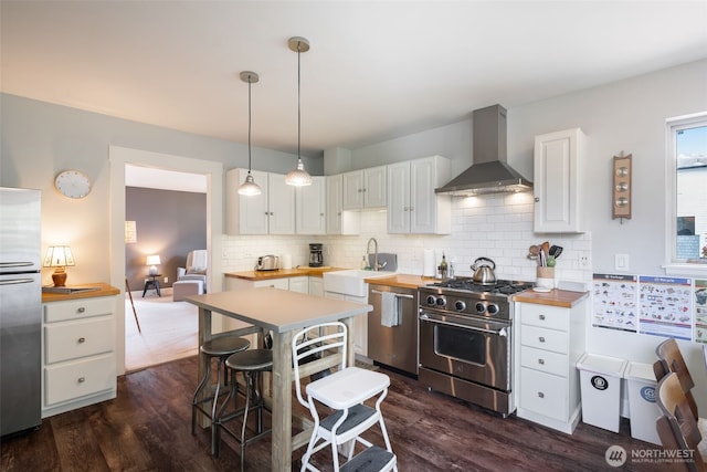 410 N 48th St, Seattle, WA 98103 - kitchen featuring stainless steel appliances, a sink, wall chimney range hood, butcher block counters, and white cabinets