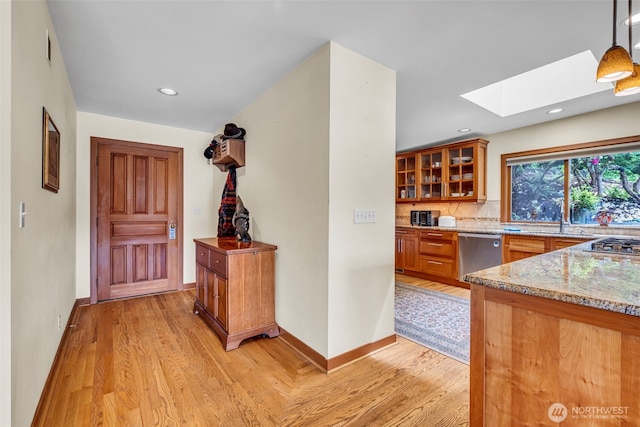 6490 NE Monte Vista Dr, Bainbridge Island, WA 98110 - kitchen featuring stainless steel dishwasher, a skylight, light wood-style flooring, light stone countertops, and recessed lighting