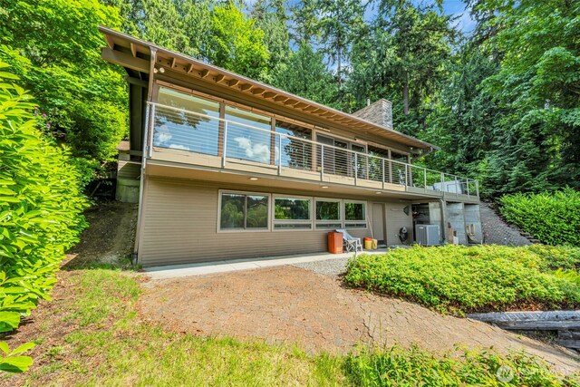 6490 NE Monte Vista Dr, Bainbridge Island, WA 98110 - back of property featuring a balcony, a chimney, and a patio area