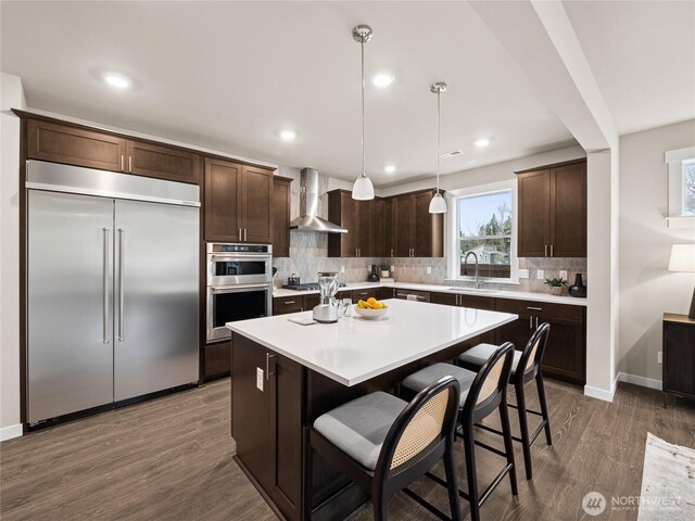 8310 115th Pl SE Unit 3, Newcastle, WA 98056 - kitchen featuring appliances with stainless steel finishes, wall chimney range hood, dark brown cabinets, a sink, and wood finished floors