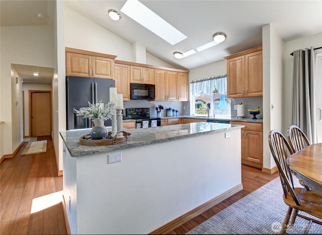 608 Harvest Rd, Bothell, WA 98012 - kitchen with black appliances, a skylight, decorative backsplash, light wood-type flooring, and a center island