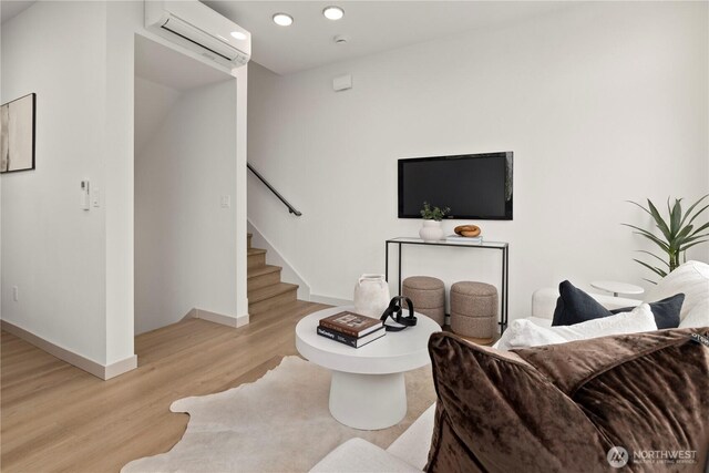 724 N 36th St, Seattle, WA 98103 - living room featuring a wall unit AC, light wood-style flooring, baseboards, stairway, and recessed lighting