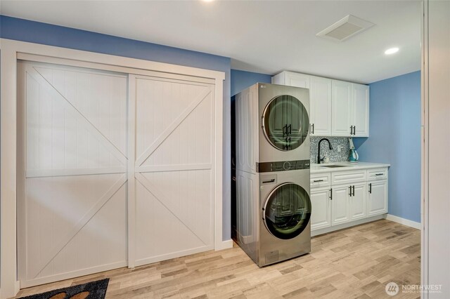 18008 Ashworth Ave N, Shoreline, WA 98133 - laundry area featuring stacked washing machine and dryer, cabinet space, light wood-style flooring, baseboards, and recessed lighting