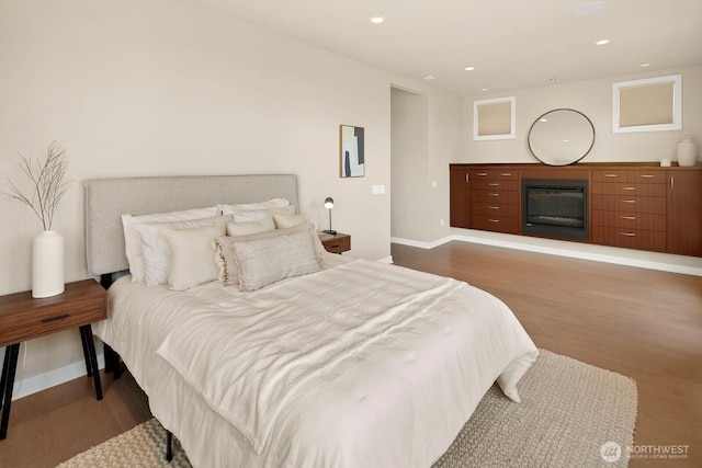 1311 Palm Ave SW, Seattle, WA 98116 - bedroom featuring wood finished floors, baseboards, a glass covered fireplace, and recessed lighting