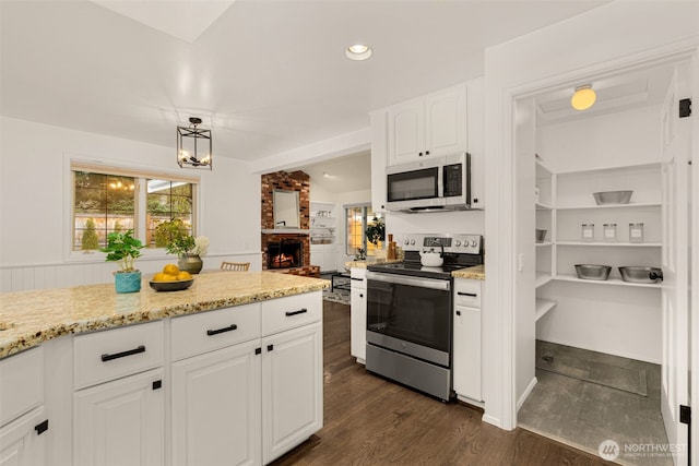 21024 NE 36th St, Sammamish, WA 98074 - kitchen with stainless steel appliances, white cabinetry, a brick fireplace, dark wood-type flooring, and light stone counters