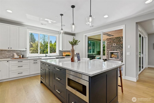 15535 NE 60th St, Redmond, WA 98052 - kitchen with white cabinets, light wood finished floors, tasteful backsplash, stainless steel microwave, and recessed lighting