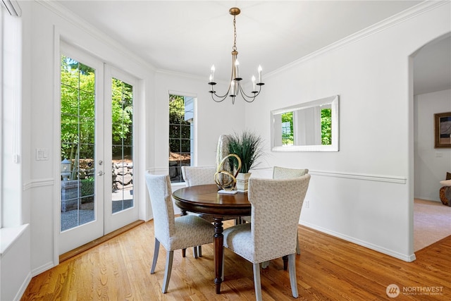 7817 NE 112th St, Kirkland, WA 98034 - dining space featuring plenty of natural light, a chandelier, arched walkways, wood finished floors, and ornamental molding