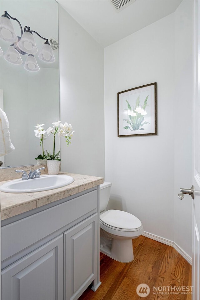 7817 NE 112th St, Kirkland, WA 98034 - half bath featuring wood finished floors, vanity, toilet, and baseboards