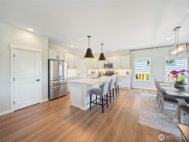 208 Hovey St, Buckley, WA 98321 - kitchen with stainless steel appliances, a sink, light wood finished floors, tasteful backsplash, and white cabinets