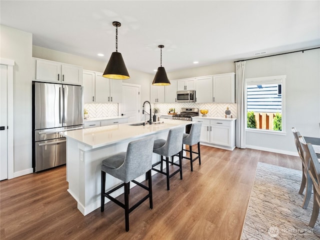208 Hovey St, Buckley, WA 98321 - kitchen featuring stainless steel appliances, a sink, white cabinets, decorative backsplash, and light wood-style flooring