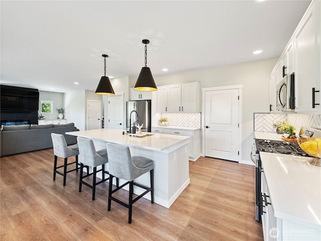 208 Hovey St, Buckley, WA 98321 - kitchen featuring appliances with stainless steel finishes, a sink, a breakfast bar area, white cabinets, and decorative backsplash