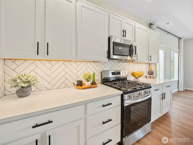 208 Hovey St, Buckley, WA 98321 - kitchen featuring stainless steel appliances, white cabinets, light countertops, and tasteful backsplash