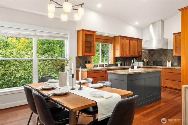 11005 NE 100th Pl, Kirkland, WA 98033 - kitchen with wall chimney exhaust hood, a sink, backsplash, brown cabinets, and wood finished floors