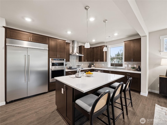 8307 115th Pl SE Unit 26, Newcastle, WA 98056 - kitchen featuring appliances with stainless steel finishes, wall chimney exhaust hood, dark brown cabinets, a sink, and dark wood-style floors
