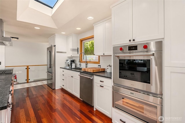 7440 SE 32nd St, Mercer Island, WA 98040 - kitchen with appliances with stainless steel finishes, a skylight, white cabinets, dark wood-style floors, and recessed lighting