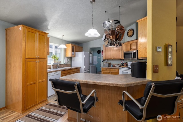 8321 S Main St, Lyman, WA 98263 - kitchen with white appliances, a peninsula, vaulted ceiling, a kitchen breakfast bar, and a textured ceiling