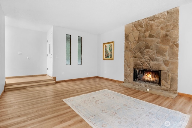 19029 56th Ln NE, Kenmore, WA 98028 - unfurnished living room featuring wood finished floors, a stone fireplace, and baseboards