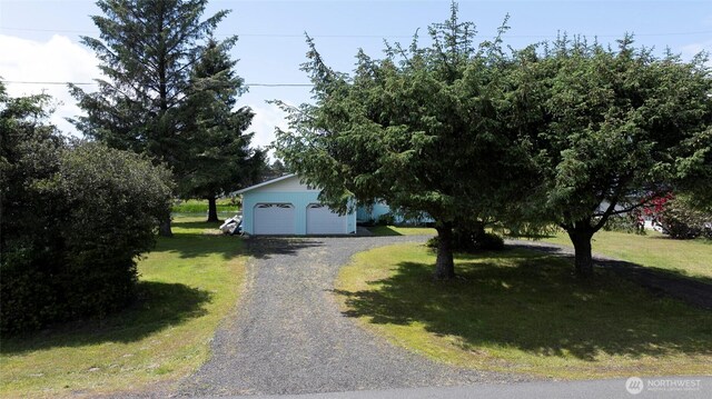 393 Canal Dr SE, Ocean Shores, WA 98569 - view of property hidden behind natural elements featuring a detached garage and a front lawn