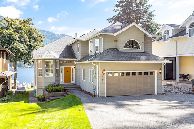 562 W Lake Samish Dr, Bellingham, WA 98229 - traditional-style house featuring a shingled roof, concrete driveway, a front lawn, and a water and mountain view