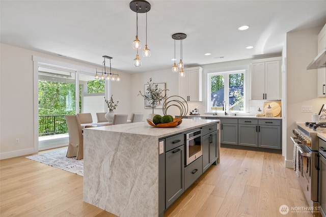 15001 NE 8th St, Bellevue, WA 98007 - kitchen featuring range with two ovens, light wood-style floors, a kitchen island, decorative backsplash, and recessed lighting