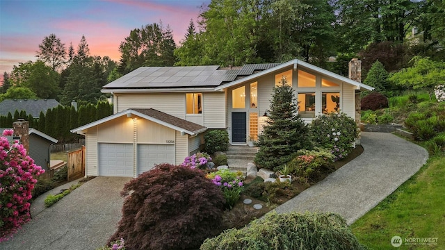 13206 SE 57th St, Bellevue, WA 98006 - view of front of house featuring solar panels, a chimney, concrete driveway, and an attached garage