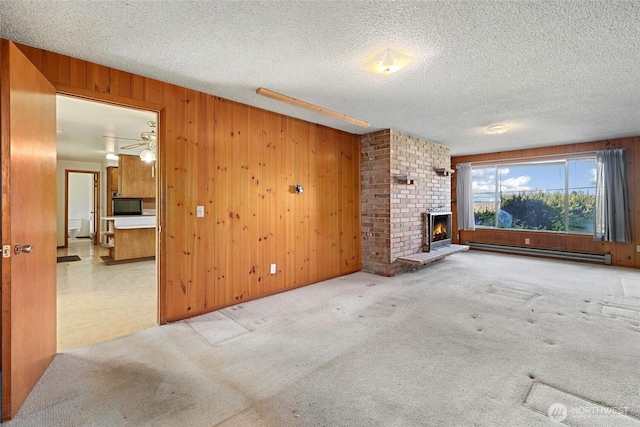 3115 43rd Ave NE, Tacoma, WA 98422 - unfurnished living room featuring a baseboard heating unit, wooden walls, a brick fireplace, carpet floors, and a textured ceiling