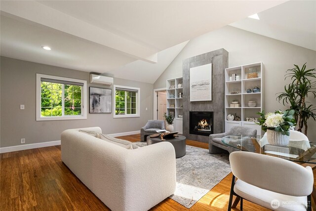 761 Chuckanut Dr, Bellingham, WA 98229 - living room with a wall mounted AC, vaulted ceiling, baseboards, wood finished floors, and a fireplace