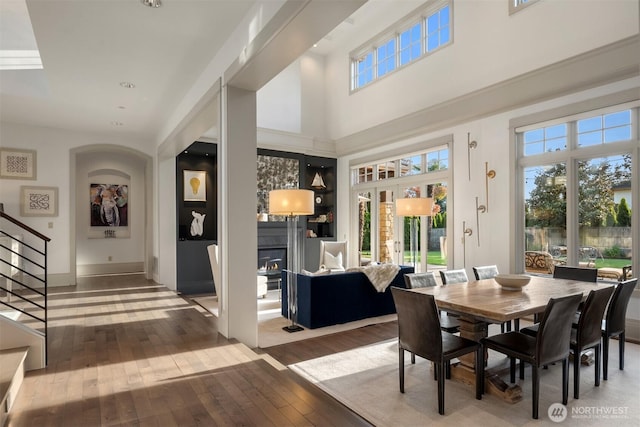 9420 NE 31st St, Clyde Hill, WA 98004 - dining space featuring hardwood / wood-style flooring, a glass covered fireplace, stairs, and a high ceiling