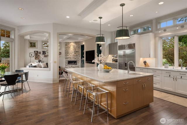 9420 NE 31st St, Clyde Hill, WA 98004 - kitchen featuring built in refrigerator, a large island, arched walkways, dark wood-style floors, and light stone counters