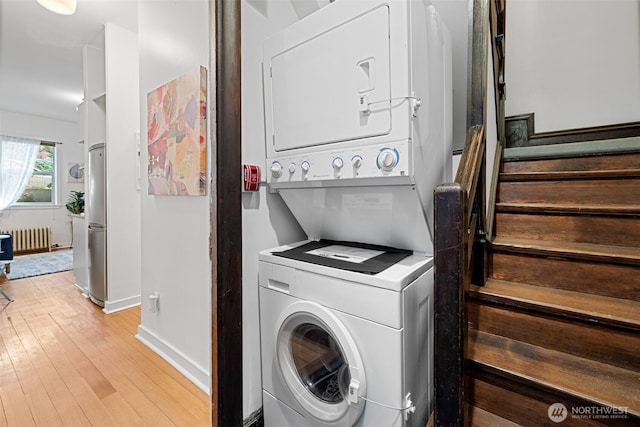 129 Warren Ave N Unit 18, Seattle, WA 98109 - laundry room featuring estacked washer and dryer, radiator, baseboards, and light wood finished floors