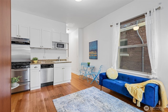 129 Warren Ave N Unit 18, Seattle, WA 98109 - kitchen with appliances with stainless steel finishes, light wood-style flooring, and white cabinets