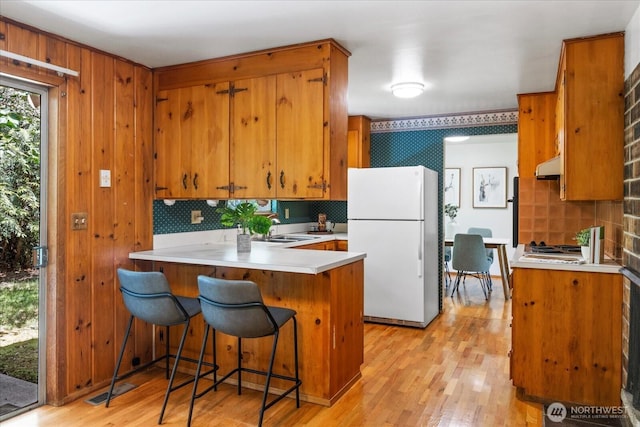9125 221st St SW, Edmonds, WA 98026 - kitchen featuring freestanding refrigerator, under cabinet range hood, brown cabinets, and decorative backsplash