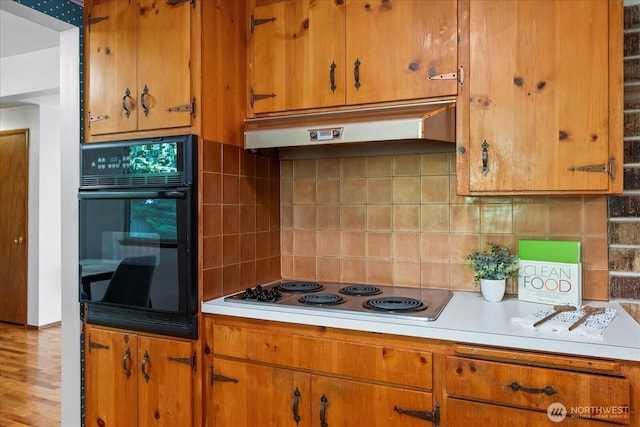 9125 221st St SW, Edmonds, WA 98026 - kitchen with under cabinet range hood, black oven, light countertops, electric stovetop, and tasteful backsplash