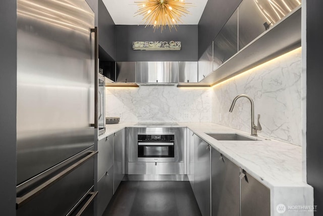 1425 Western Ave Unit L308, Seattle, WA 98101 - kitchen with appliances with stainless steel finishes, a sink, decorative backsplash, light stone counters, and gray cabinets