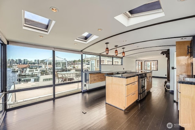 2040 Westlake Ave N Unit 26, Seattle, WA 98109 - kitchen featuring a skylight, stainless steel range with electric cooktop, light brown cabinets, dark wood finished floors, and dark countertops