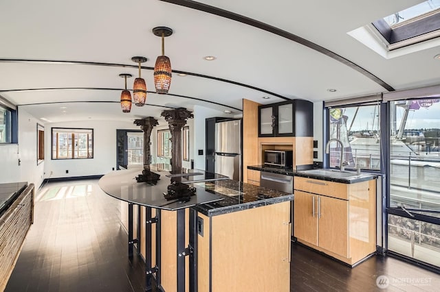 2040 Westlake Ave N Unit 26, Seattle, WA 98109 - kitchen with appliances with stainless steel finishes, dark wood-style flooring, a skylight, light brown cabinetry, and dark countertops