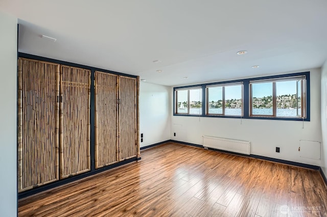 2040 Westlake Ave N Unit 26, Seattle, WA 98109 - unfurnished bedroom featuring radiator heating unit, wood finished floors, and recessed lighting