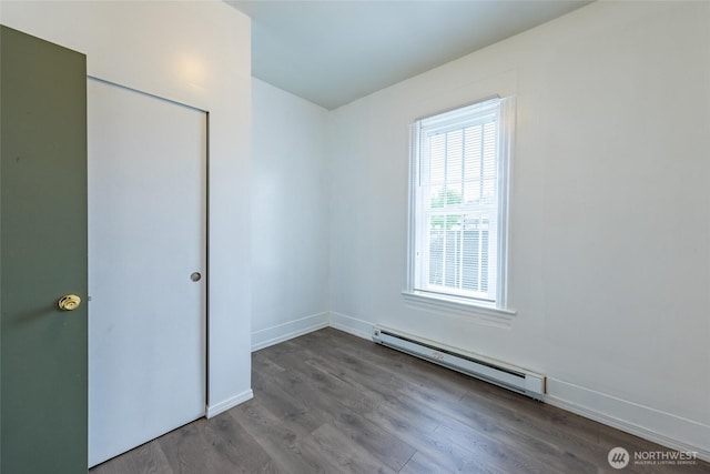 3827 S Morgan St, Seattle, WA 98118 - unfurnished bedroom with a baseboard heating unit, wood finished floors, and baseboards
