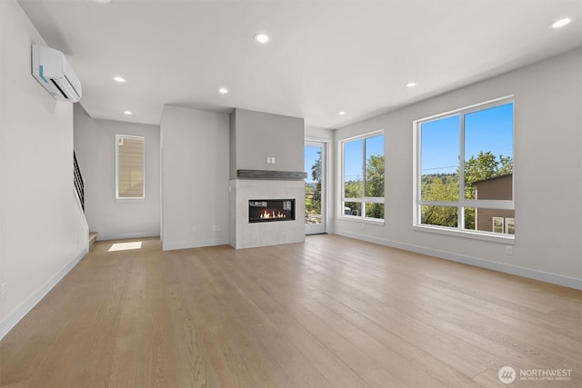 4570 22nd Ave SW, Seattle, WA 98106 - unfurnished living room with a wall mounted AC, baseboards, recessed lighting, light wood-style floors, and a glass covered fireplace