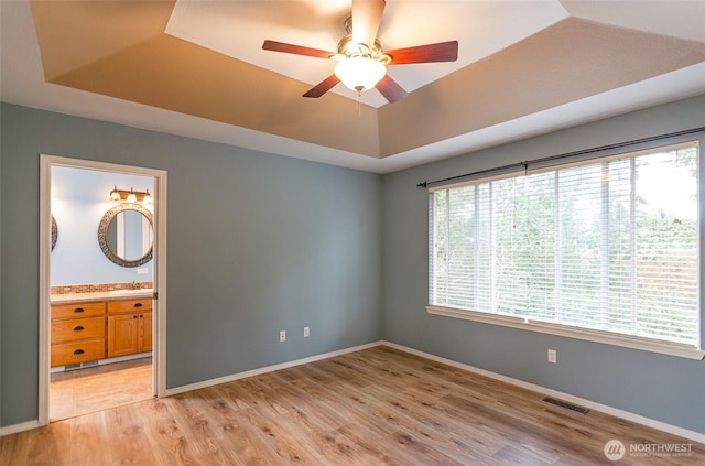 5614 Vincent Ct SE, Lacey, WA 98513 - unfurnished bedroom with a raised ceiling, light wood-style floors, connected bathroom, and ceiling fan