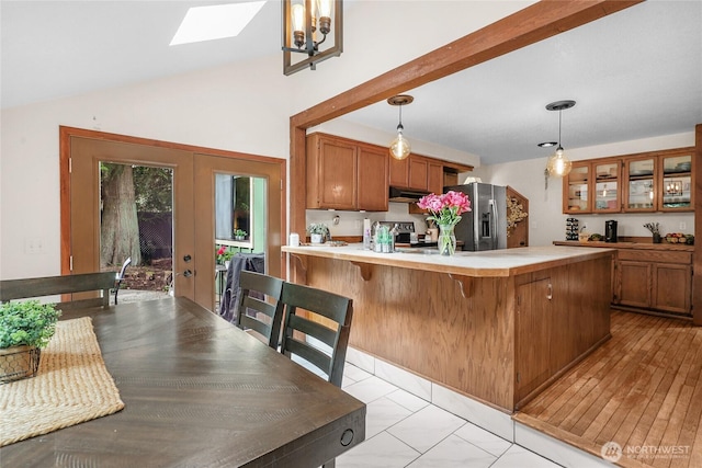 3904 Ridge Way, Mount Vernon, WA 98273 - kitchen with stainless steel refrigerator with ice dispenser, under cabinet range hood, brown cabinets, a skylight, and vaulted ceiling