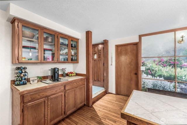 3904 Ridge Way, Mount Vernon, WA 98273 - kitchen featuring light wood-style floors, brown cabinetry, glass insert cabinets, a textured ceiling, and tile countertops