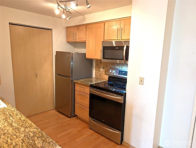 6960 California Ave SW Unit A104, Seattle, WA 98136 - kitchen with stainless steel appliances, light wood-type flooring, tasteful backsplash, light brown cabinets, and stone counters