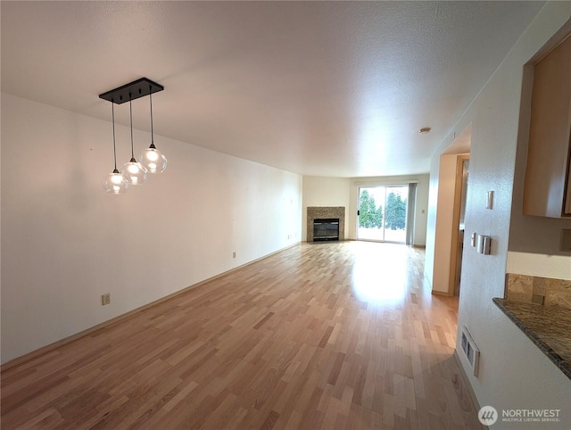 6960 California Ave SW Unit A104, Seattle, WA 98136 - unfurnished living room featuring light wood-style flooring and a glass covered fireplace