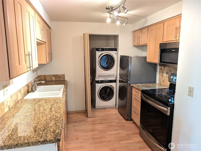 6960 California Ave SW Unit A104, Seattle, WA 98136 - kitchen featuring appliances with stainless steel finishes, stacked washer and clothes dryer, backsplash, light wood-style flooring, and light brown cabinetry