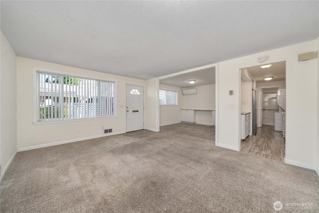330 7th Pl SE Unit 4, Puyallup, WA 98372 - unfurnished living room with carpet, a wall mounted air conditioner, baseboards, and a textured ceiling
