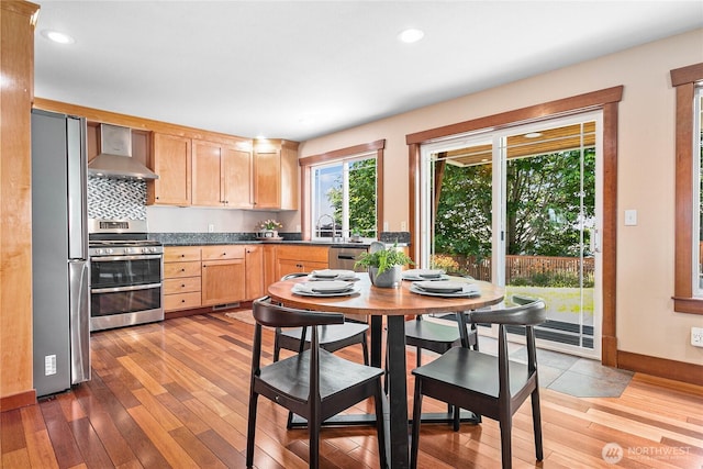 3276 Spyglass Dr, Bellingham, WA 98226 - kitchen with stainless steel appliances, wall chimney exhaust hood, light brown cabinets, light wood-style floors, and dark countertops