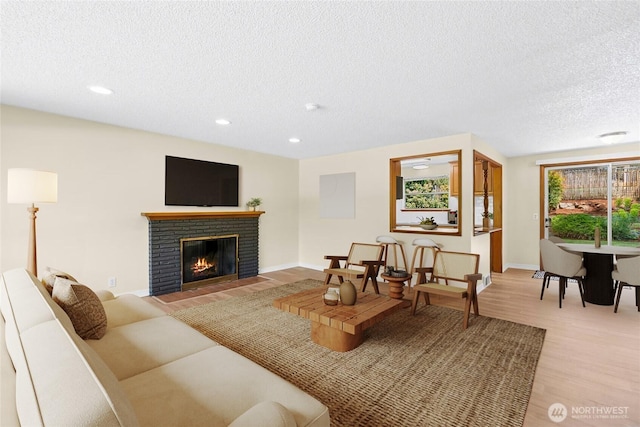 20608 1st Ave S, Des Moines, WA 98198 - living room with light wood-type flooring, a textured ceiling, a fireplace, recessed lighting, and baseboards
